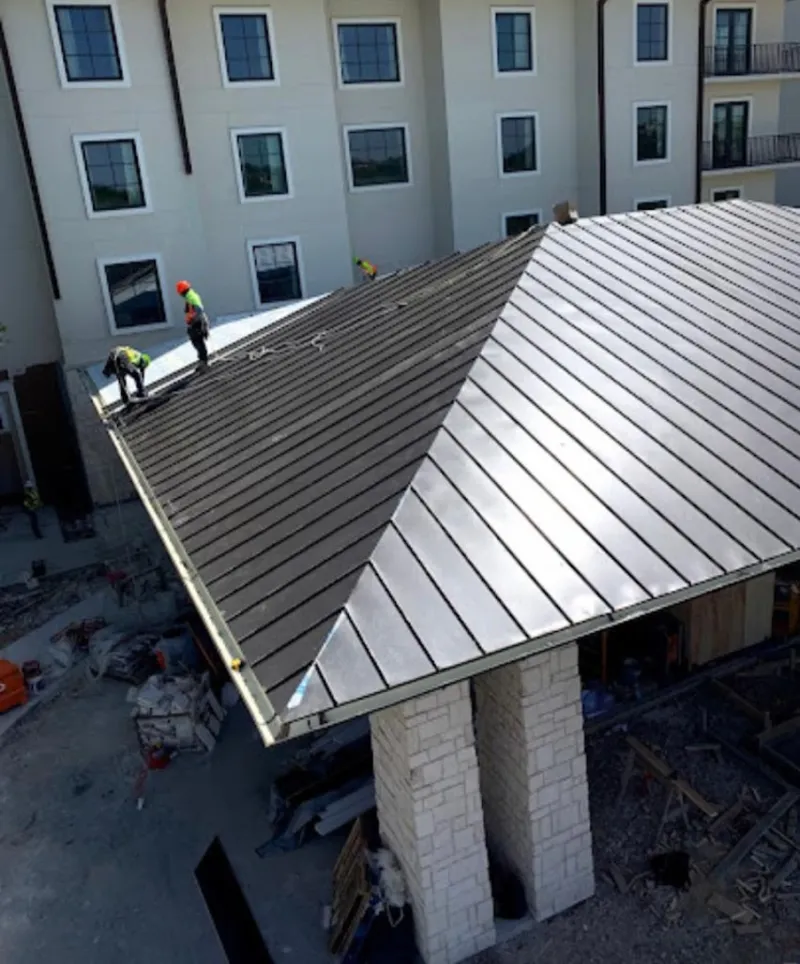 Crew installing standing seam metal roof panels on a commercial project in Texarkana